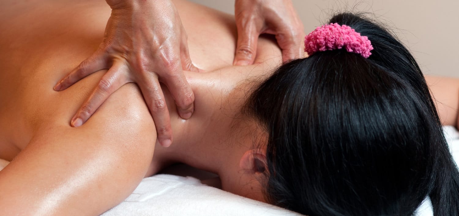 Thai massage therapists doing a neck massage for a female client.
